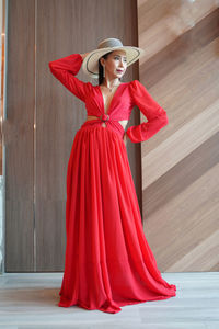 Woman wearing red hat standing against wall