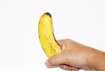 Close-up of hand holding banana against white background