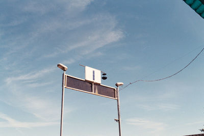 Low angle view of bird perching on street light against sky