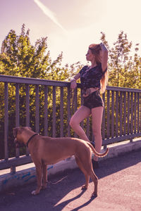Young woman standing by dog on footbridge