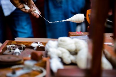 Close-up of person hand weaving cotton on table