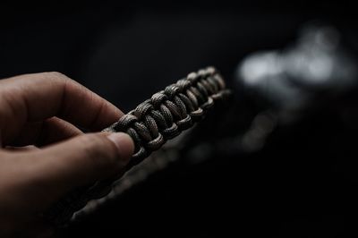 Close-up of hand holding metal against black background