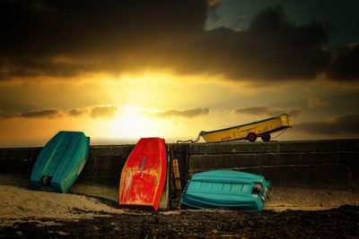 Boats moored on beach against sky during sunset