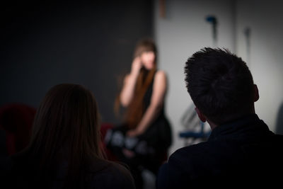 Rear view of people sitting in studio