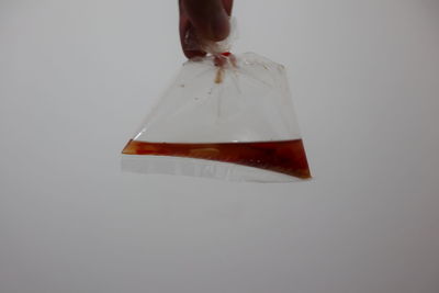 Close-up of hand holding ice cream over white background