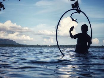 Rear view of silhouette man by sea against sky