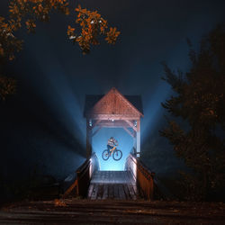 Illuminated mtb riderjumping against foggy sky at night