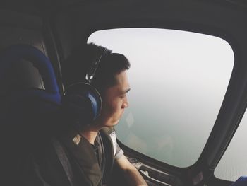 Man listening music while looking through airplane window
