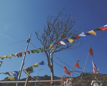 Low angle view of flags against clear blue sky