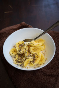 Cereal bowl with slice bananas sprinkled with chia seeds in a bowl on a dark background.