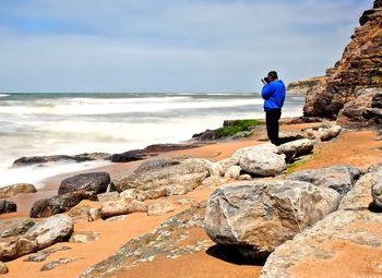 Man photographing while standing at beach