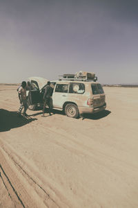 Vintage car on desert land against sky