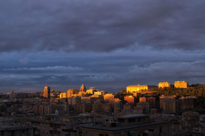 Buildings in city against dramatic sky