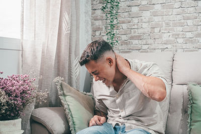 Young man sitting on sofa at home