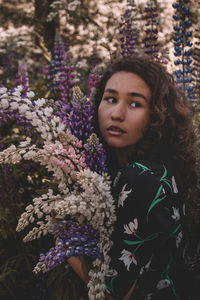 Portrait of beautiful young woman standing by flowering plants