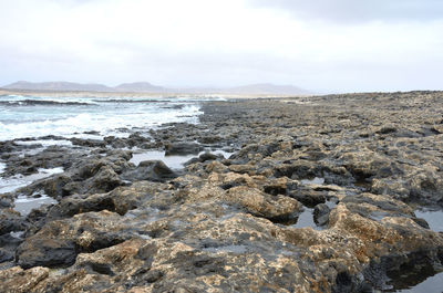 Scenic view of rocks on beach against sky