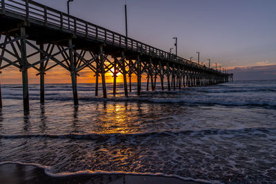 Pier over sea against sky during sunset