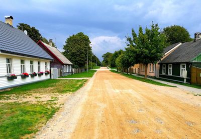 Road amidst trees and buildings against sky