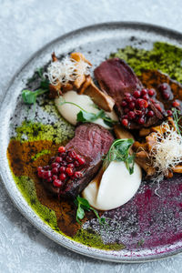 From above delicious rare steak with sweet cranberry sauce served with herbs and mushrooms with cheese on plate