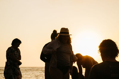 People looking at sea against clear sky