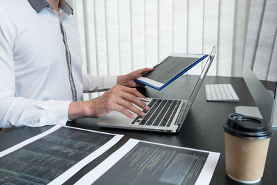 Midsection of doctor using laptop on table