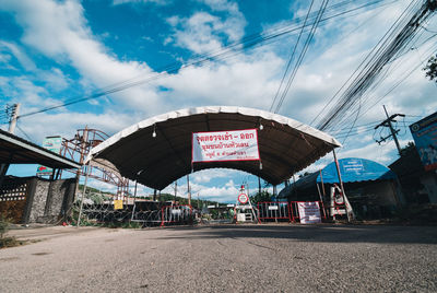 Road sign by street against sky in city