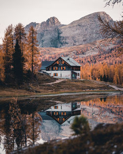 House by lake and mountains against sky