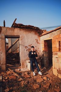 People standing by abandoned building against sky