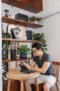 Side view of young woman using mobile phone while sitting at home