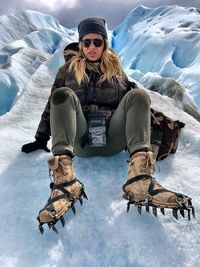 Full length portrait of woman hiking on snowcapped mountains during winter