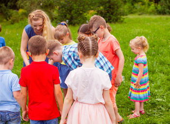 Kids standing with woman at park