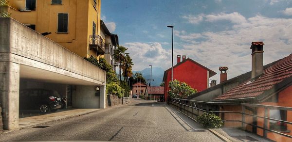 Road amidst buildings in city against sky