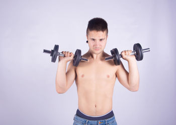 Portrait of young man with arms raised against gray background