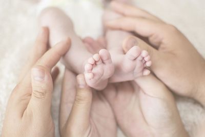 Cropped hands of parents touching baby feet