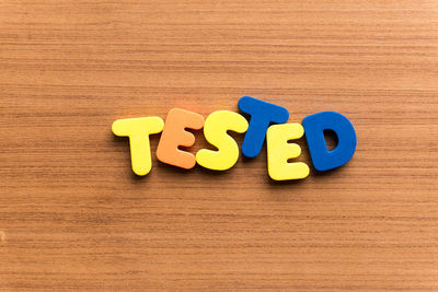 High angle view of colorful tested text on wooden table