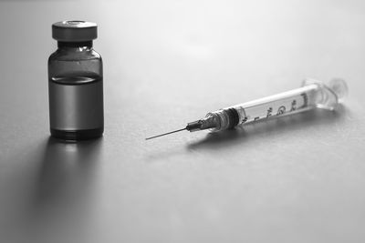 Close-up of syringe by vial on table