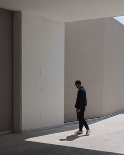 Full length of young man walking against wall