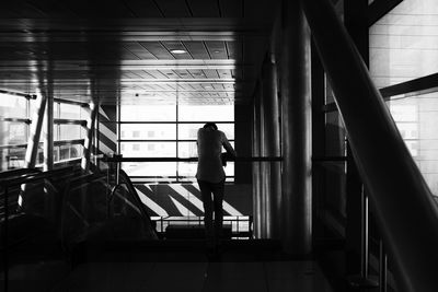 Rear view of silhouette woman standing by window in building