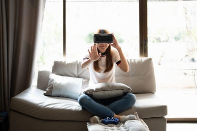 Young woman using mobile phone while sitting on sofa at home