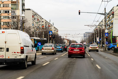 Cars on city street by buildings against sky