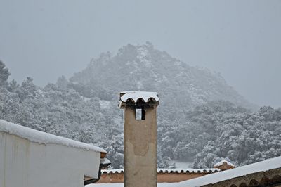 Built structure on snow covered mountain against sky