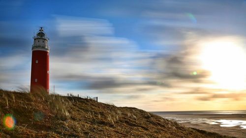 Lighthouse on beach against sky