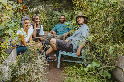 Portrait of male and female farmers sitting in organic farm