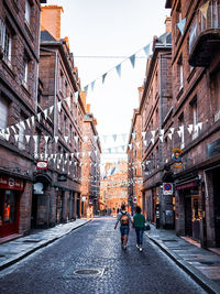 People walking on street amidst buildings in city