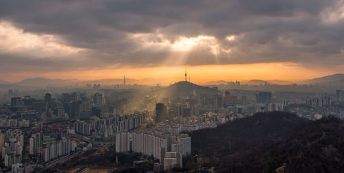 Cityscape against cloudy sky during sunset