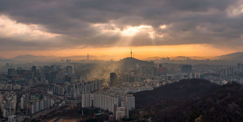 Cityscape against cloudy sky during sunset