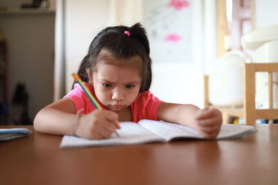 Portrait of girl with open book on table