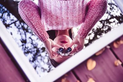 Woman with binocular reflecting on mirror