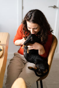 Side view of young woman with dog at home