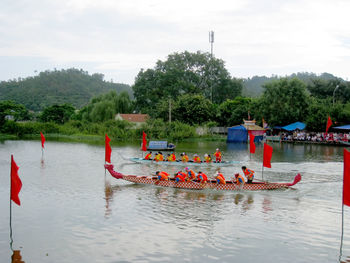 People in boat on river against sky